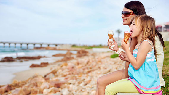 A couple in an open-top convertible parked near beach watching the sunset