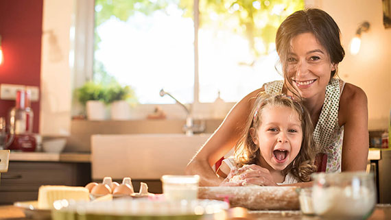 A mother helping her kids prepare a dessert in the kitchen