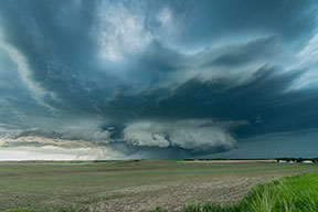 Low hanging shelf clouds with a tornado in the distance