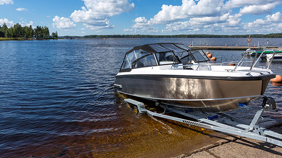 A pickup truck backing boat into lake from boat ramp