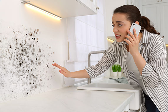 a woman observes mold on her wall and makes a phone call