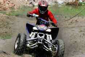 An ATV rider traversing an uneven dirt road