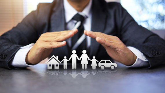 A business person uses his hands to cover a graphic of a home, family and car.