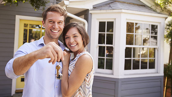 A bird's eye view of a couple laying on their backs on the floor dreaming of homeownership