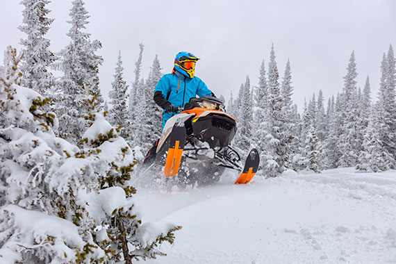 Rider on snowmobile in deep snow and wooded setting